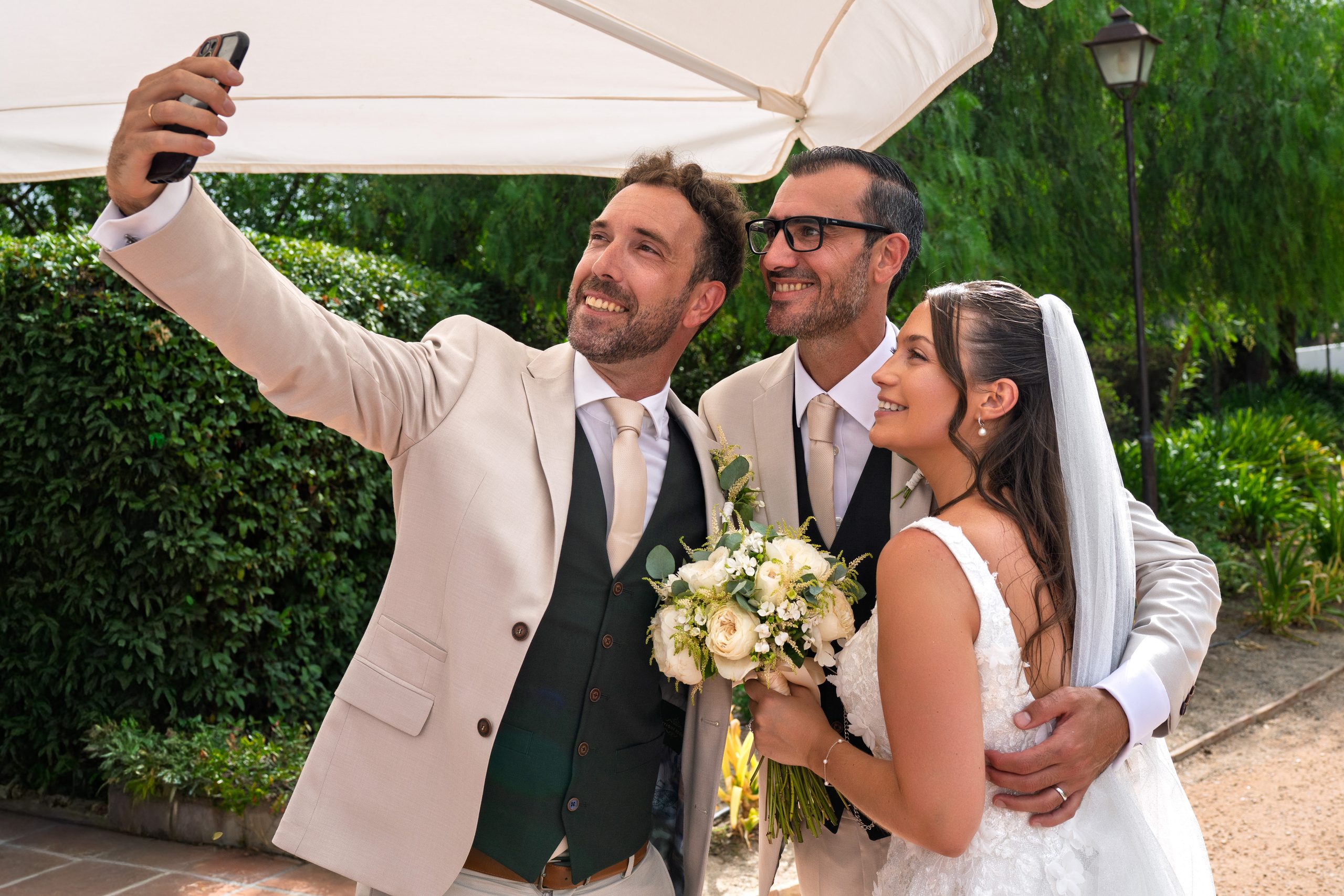 Un témoin prend un selfie avec les mariés sous un parasol — Cortijo Bravo, Vélez-Málaga