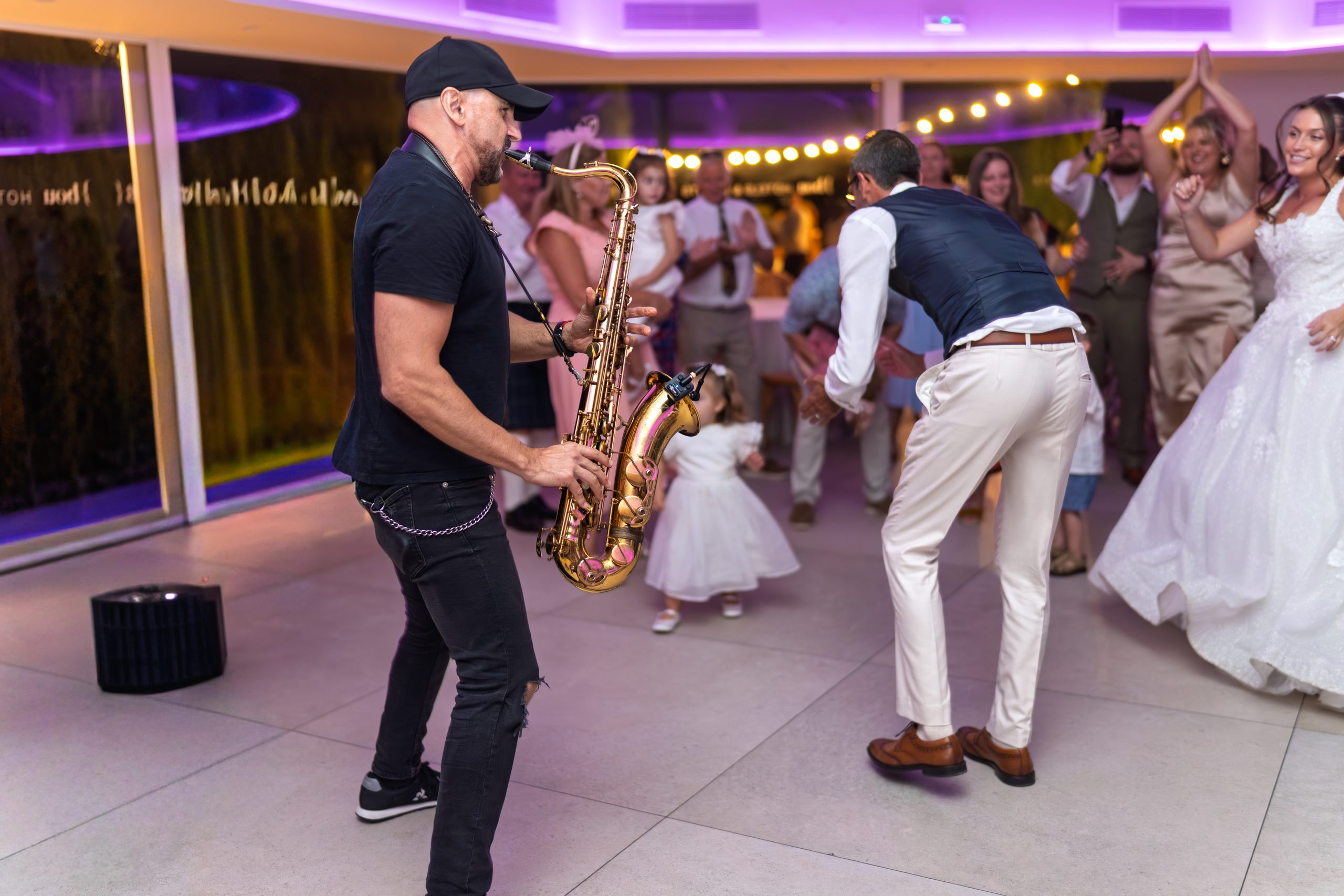 Un saxophoniste joue sur la piste pendant que le marié et la fille de la mariée dansent — Cortijo Bravo, Vélez-Málaga