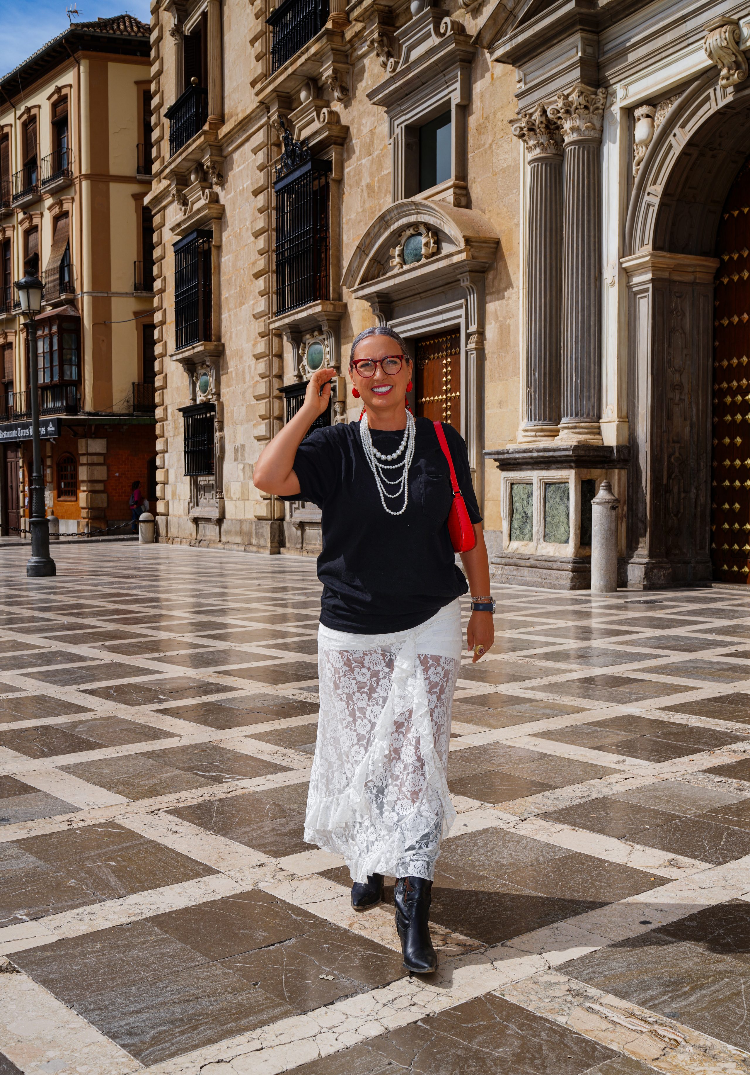 Kobieta idąca przez marmurowy plac przed rzeźbioną kamienną fasadą — Historyczne centrum, Granada