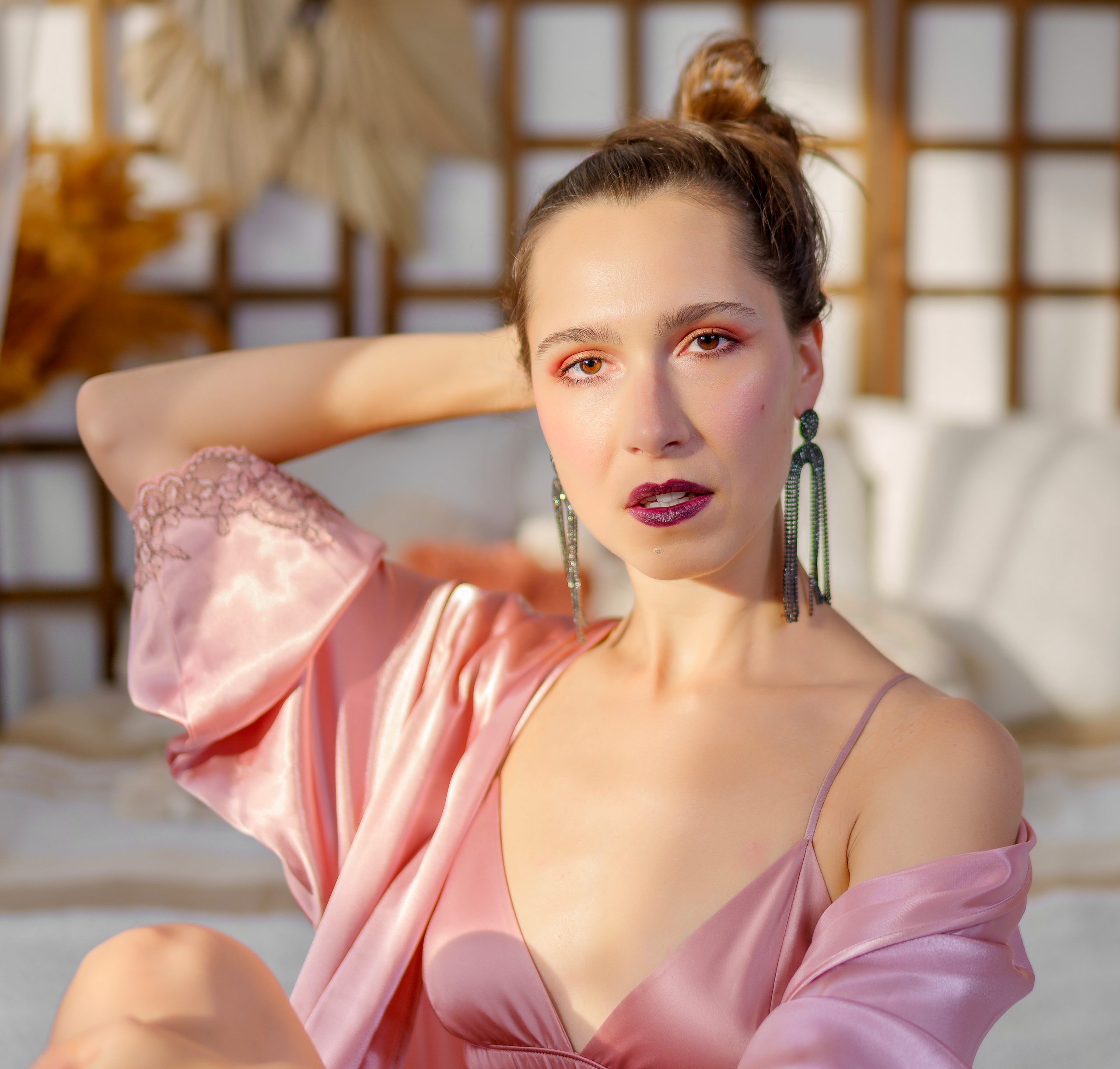 Femme en peignoir de satin rose, main derrière la tête