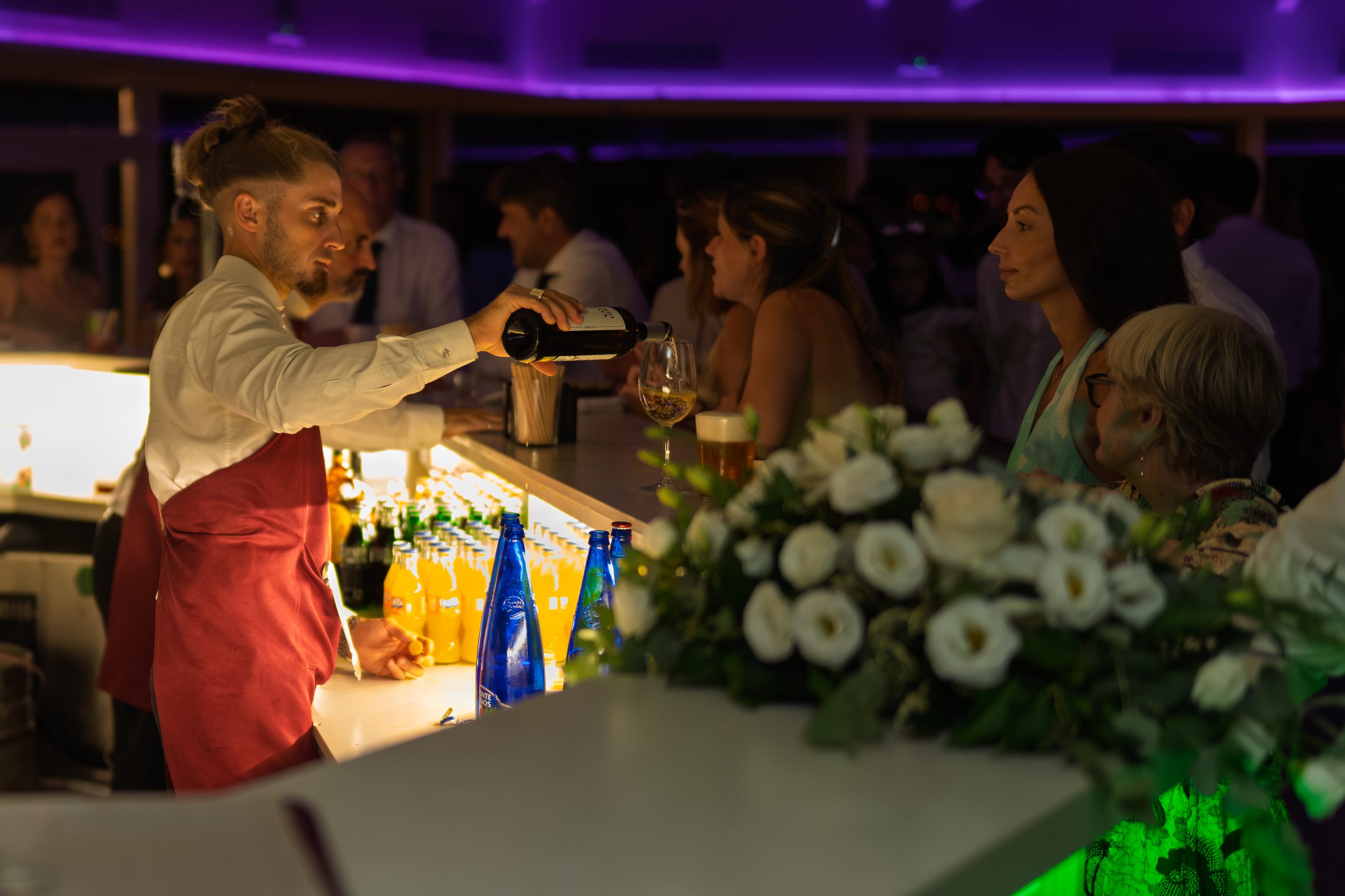 El camarero sirve vino en la barra junto a flores blancas — Cortijo Bravo, Vélez-Málaga