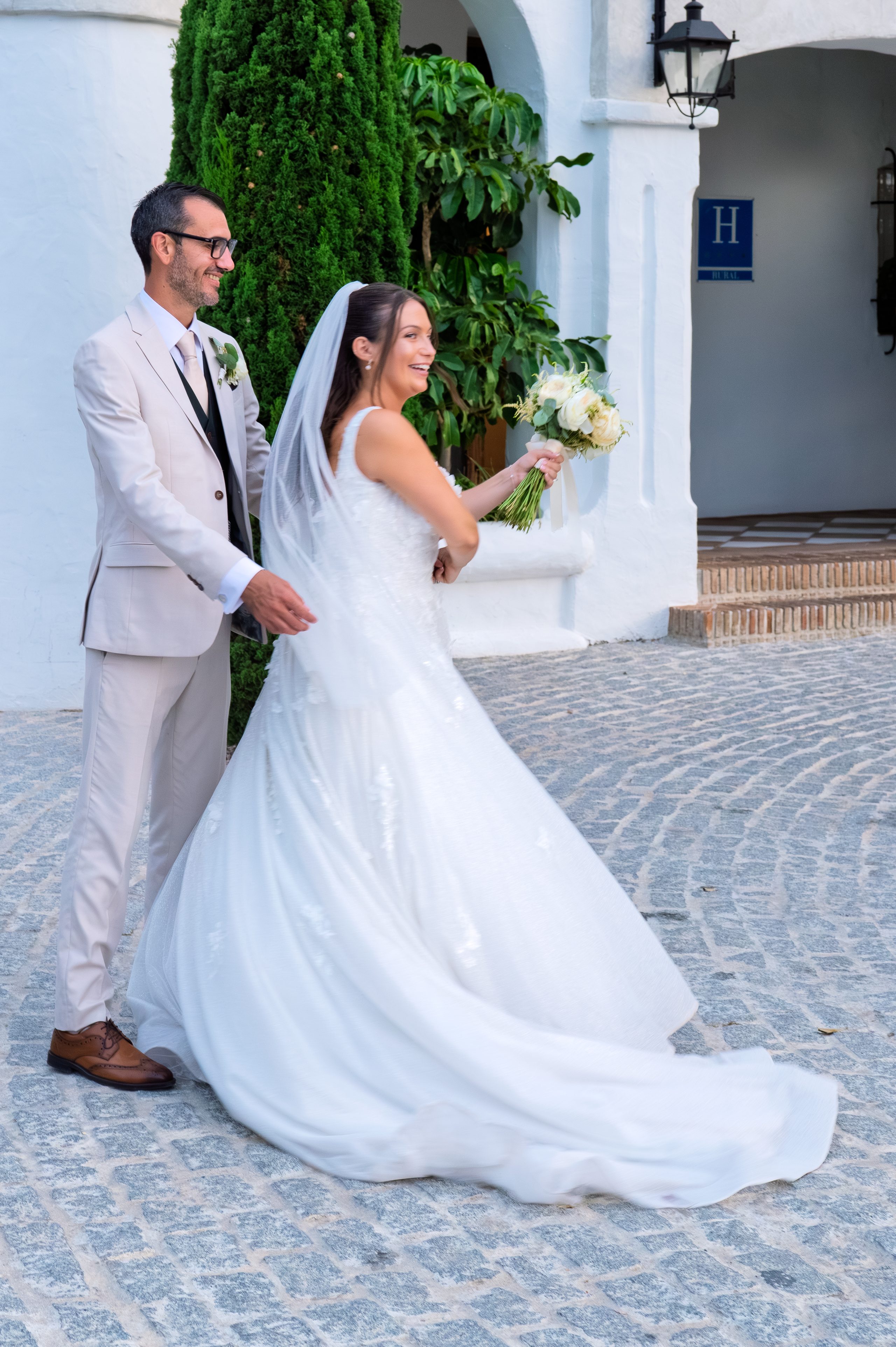 Pan młody obraca pannę młodą za rękę przy bielonym budynku — Cortijo Bravo, Vélez-Málaga