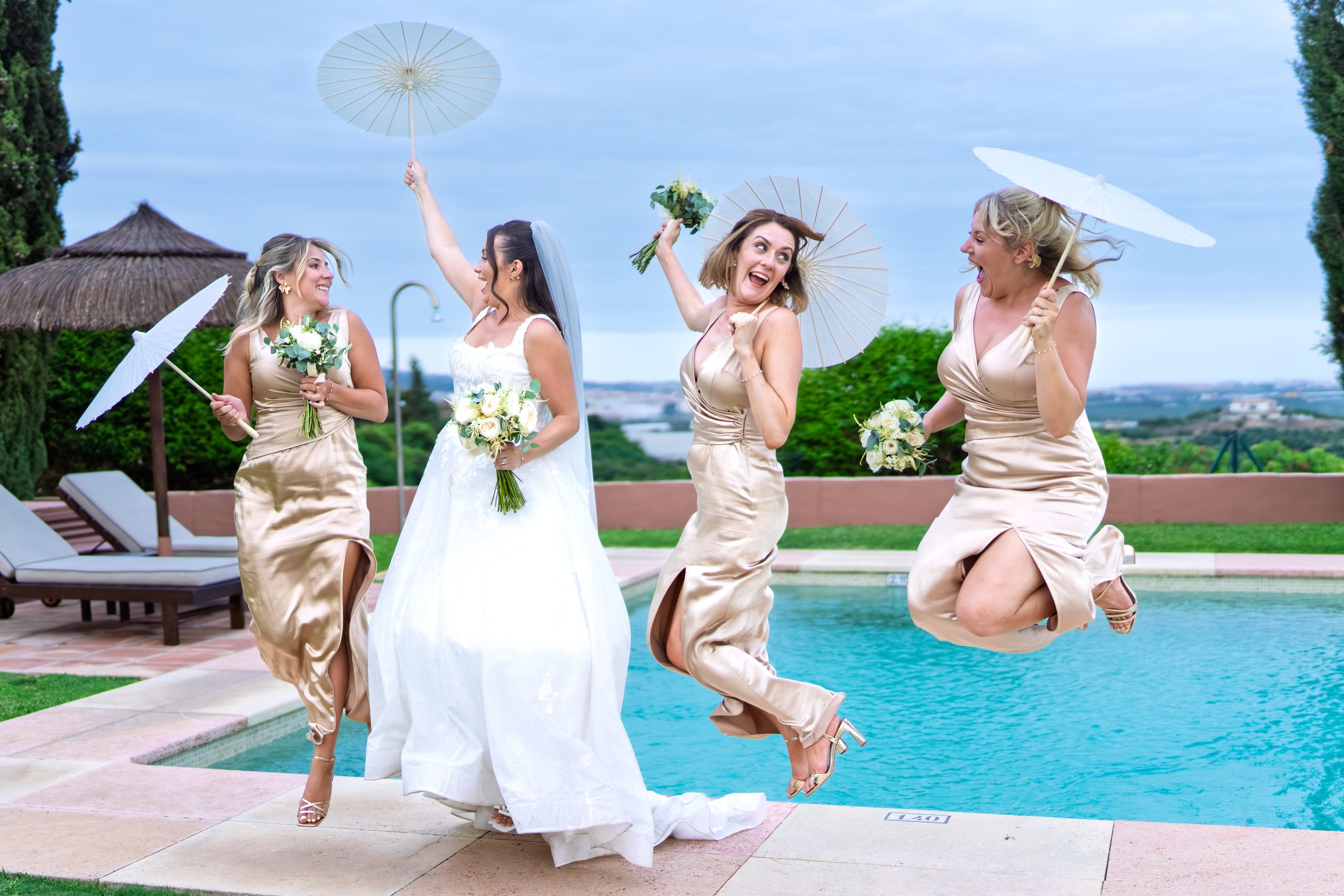 Damas de honor saltando con sombrillas junto a la piscina — Cortijo Bravo, Vélez-Málaga