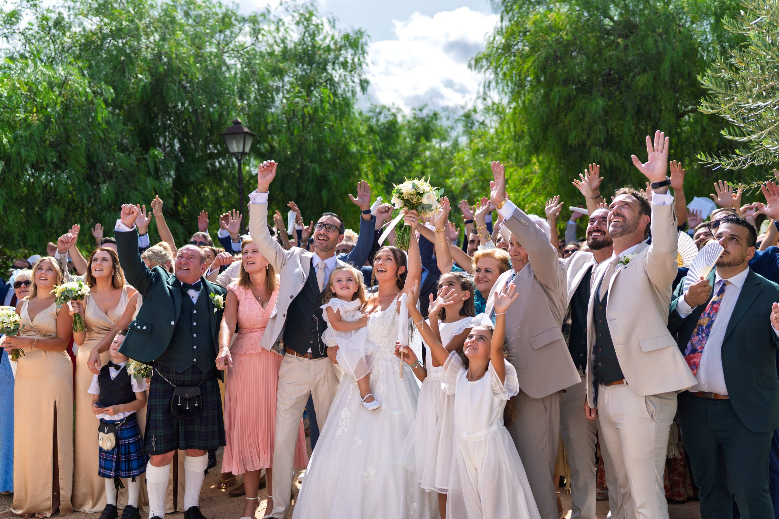 Invités qui acclament les bras en l'air, la mariée portant sa fille — Cortijo Bravo, Vélez-Málaga