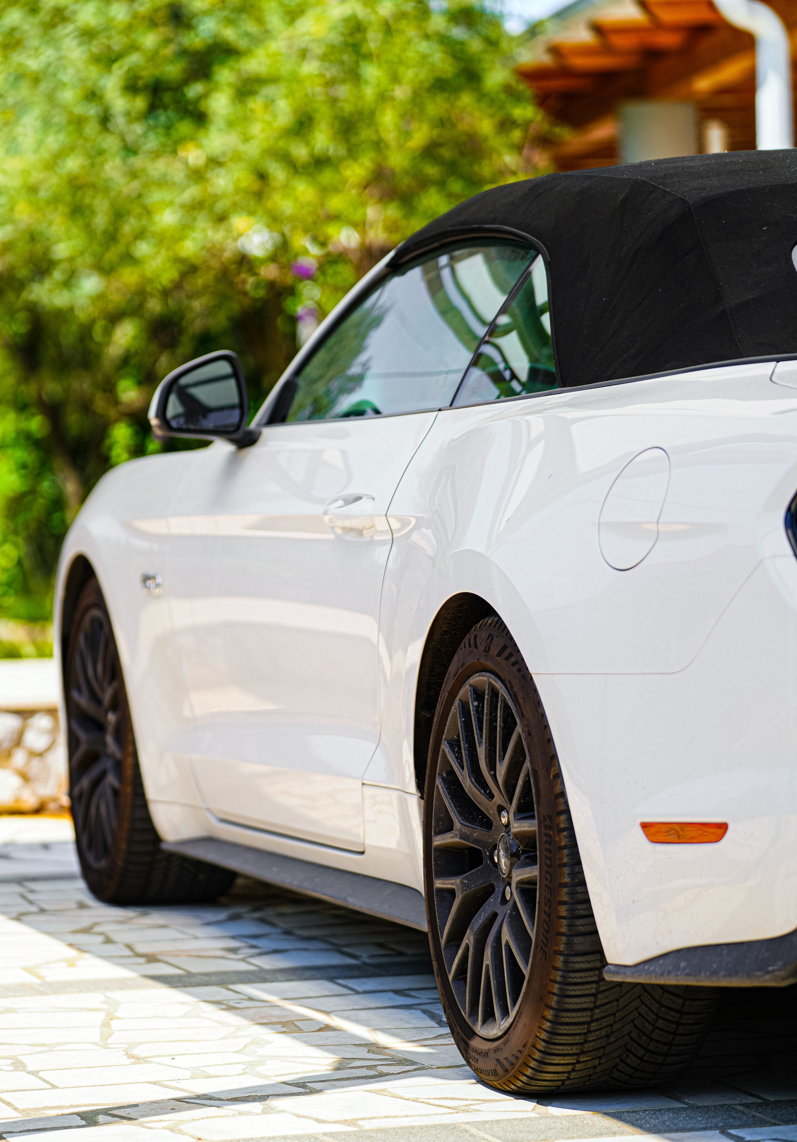 Biały Ford Mustang GT kabriolet z rozłożonym dachem w ogrodzie