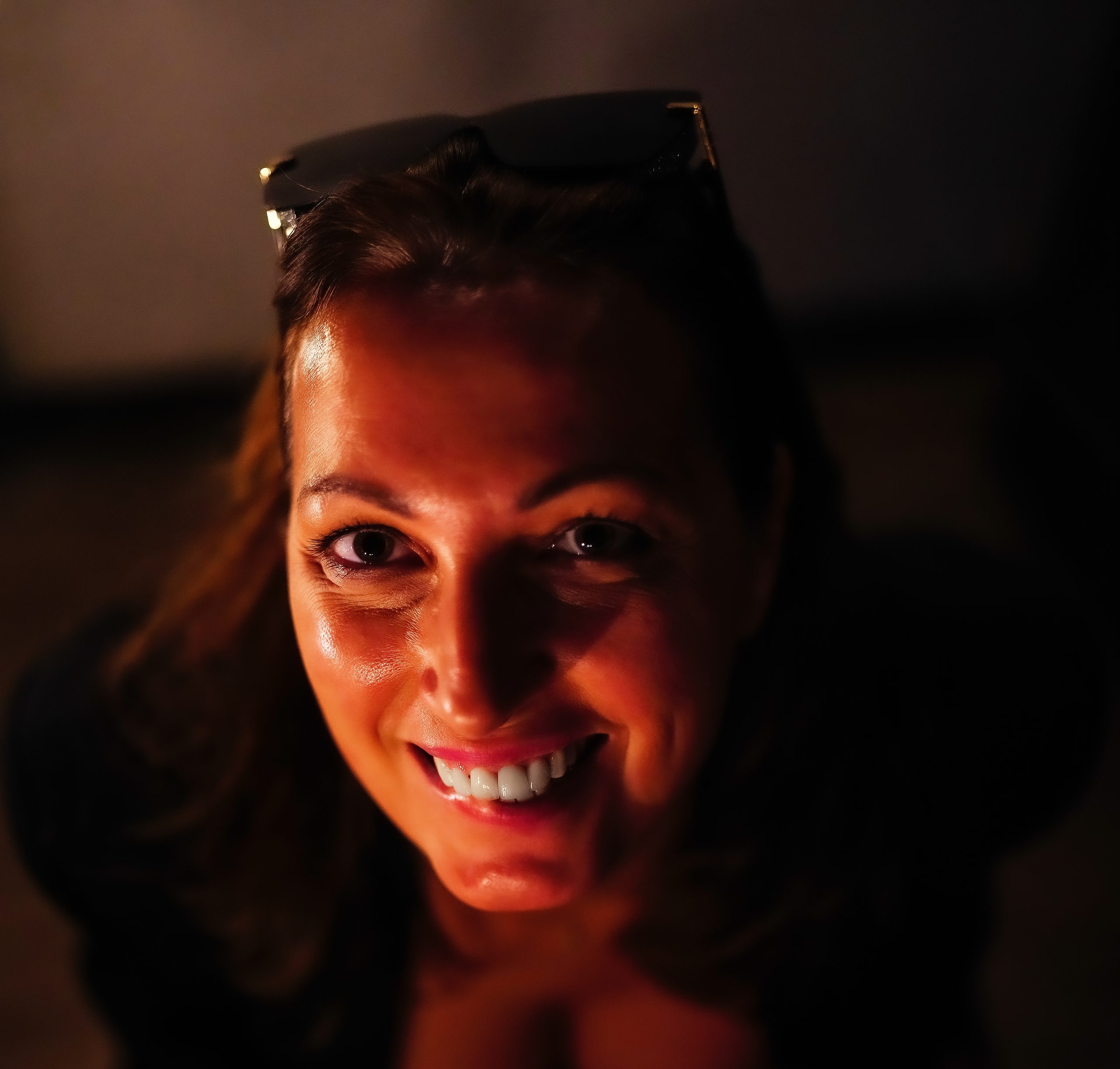 Portrait d'une femme souriante éclairée d'une lumière chaude sur fond sombre