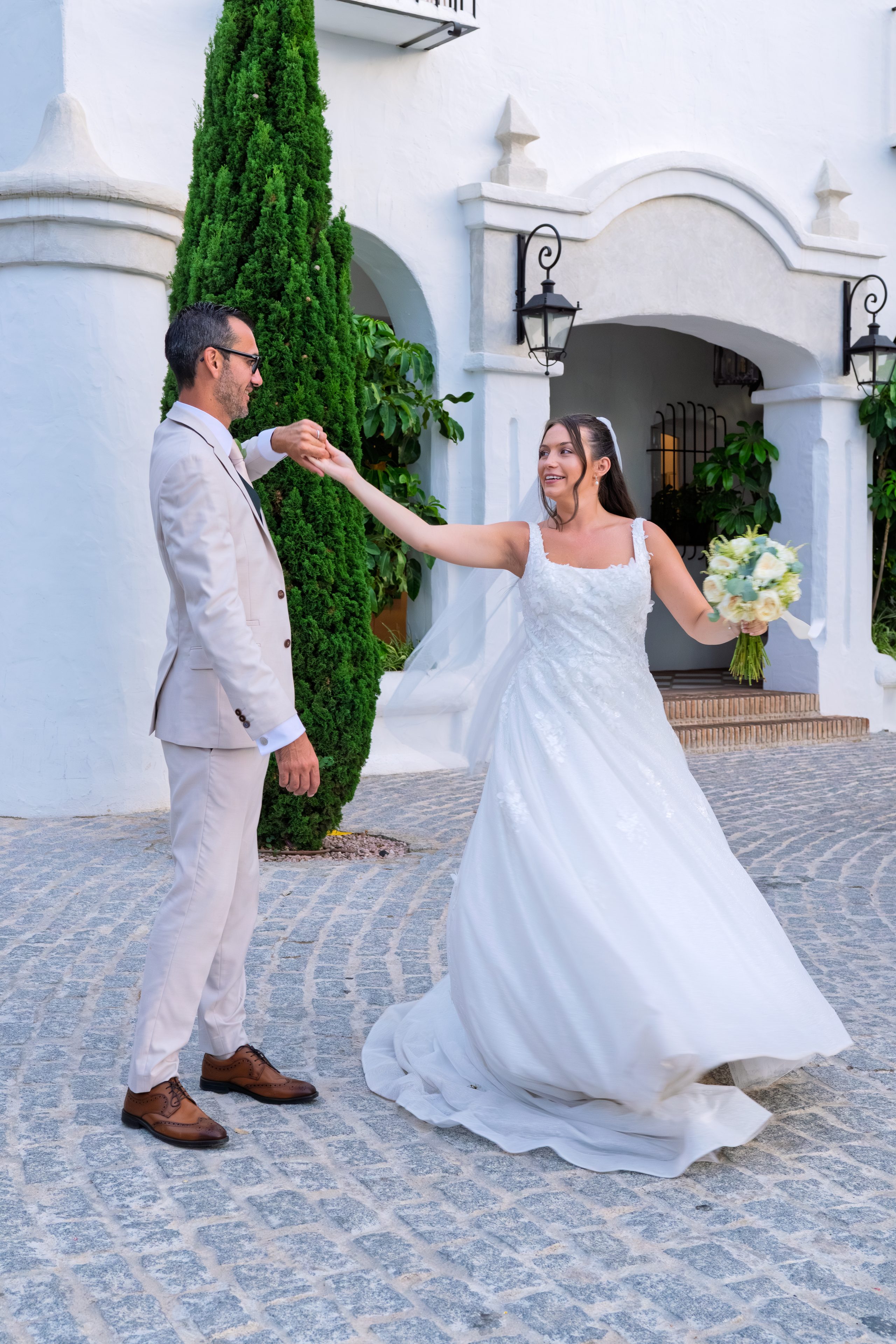 Panna młoda wiruje w sukni, pan młody trzyma ją za rękę na bruku — Cortijo Bravo, Vélez-Málaga