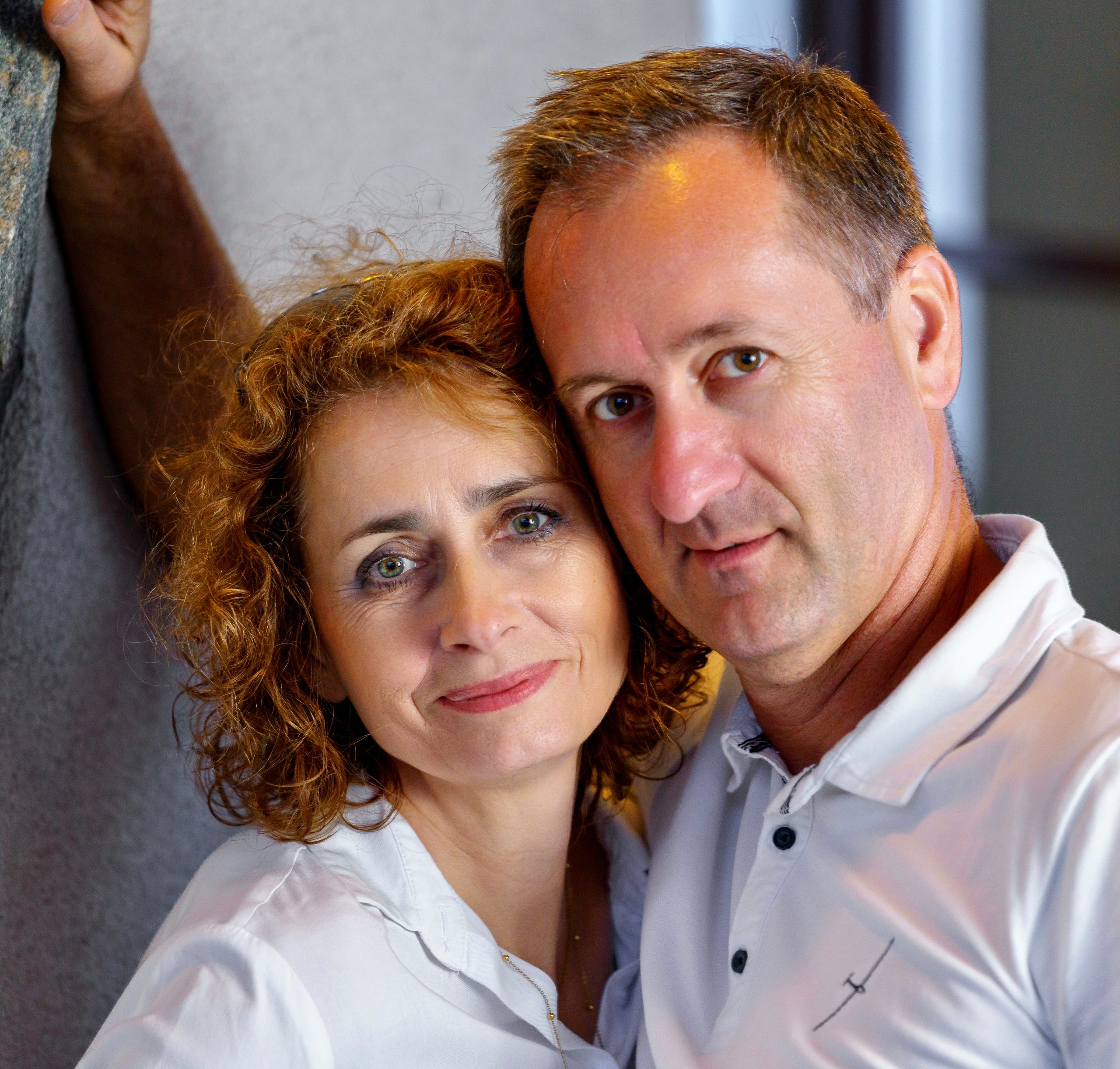 Couple joue contre joue contre un mur, regardant l'objectif