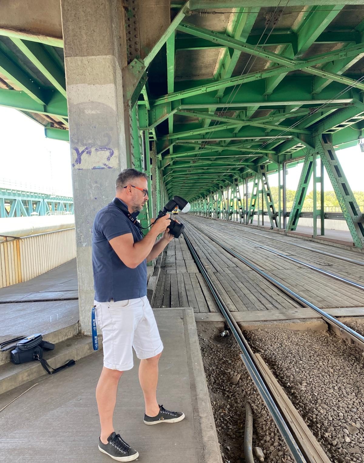 Adam Lankamer fotografiando bajo un puente de acero verde