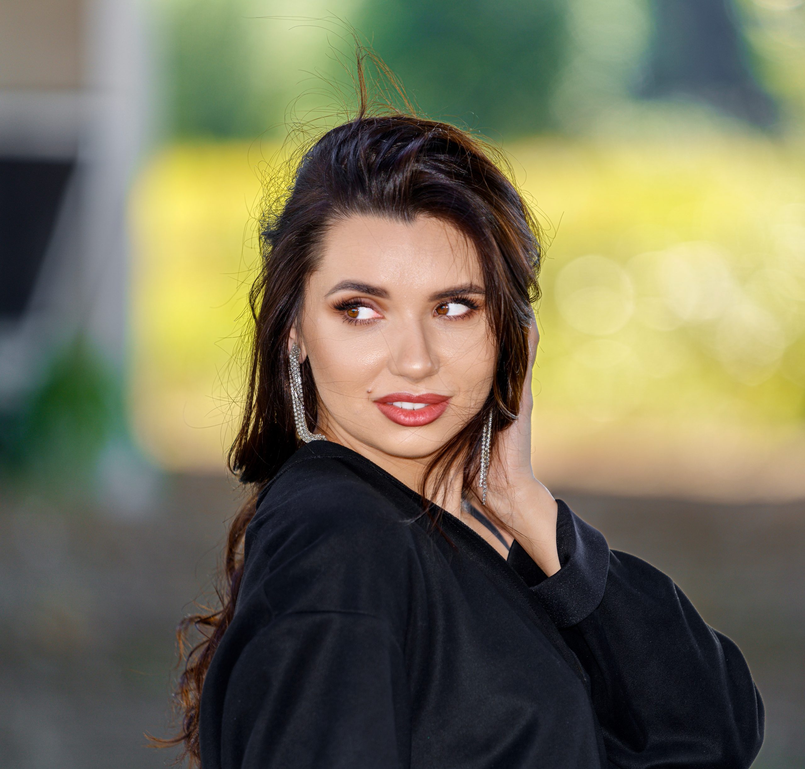 Portret brunetki w czarnej kurtce spoglądającej przez ramię