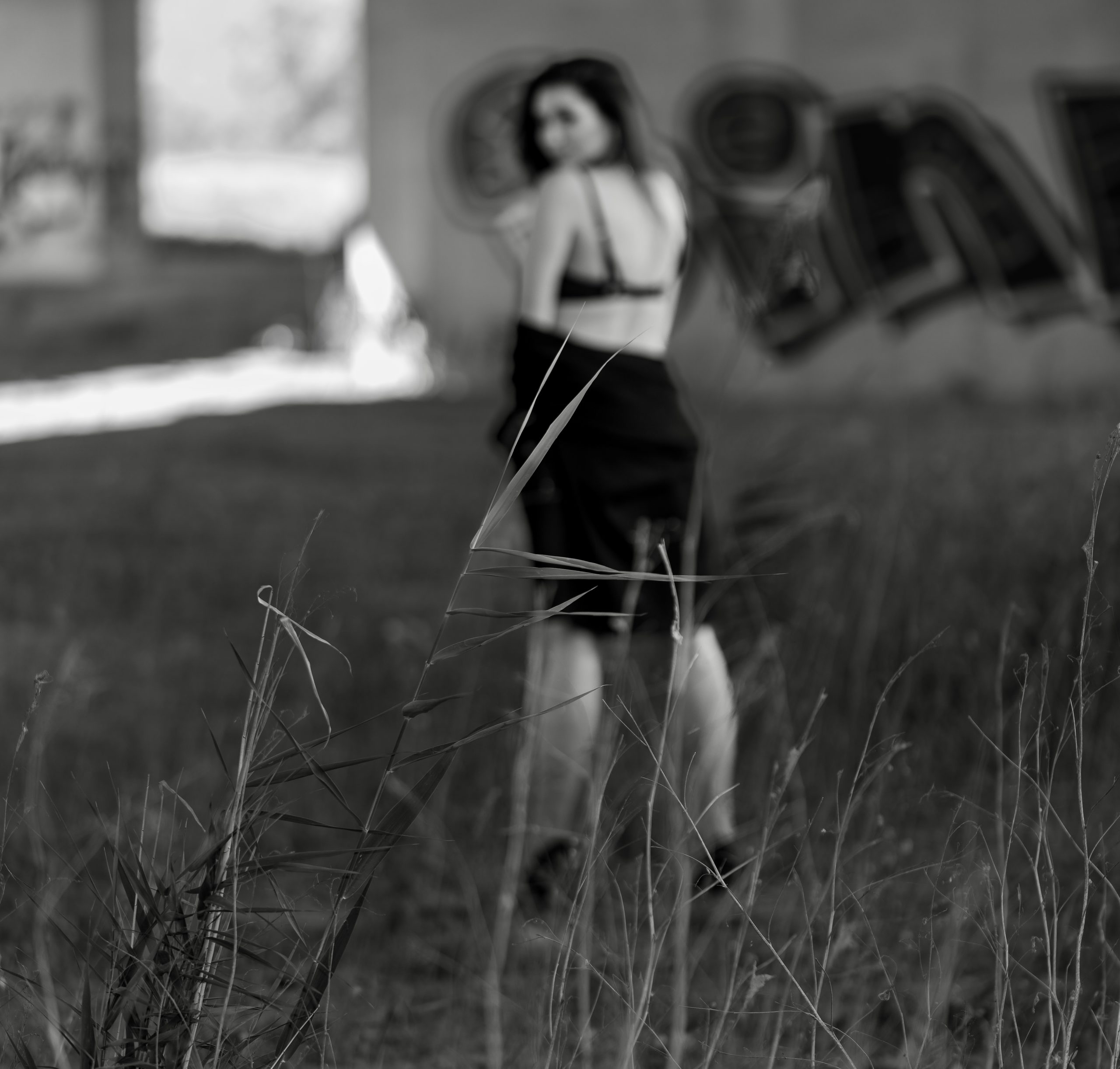 Czarno-białe zdjęcie kobiety w bieliźnie idącej w stronę graffiti