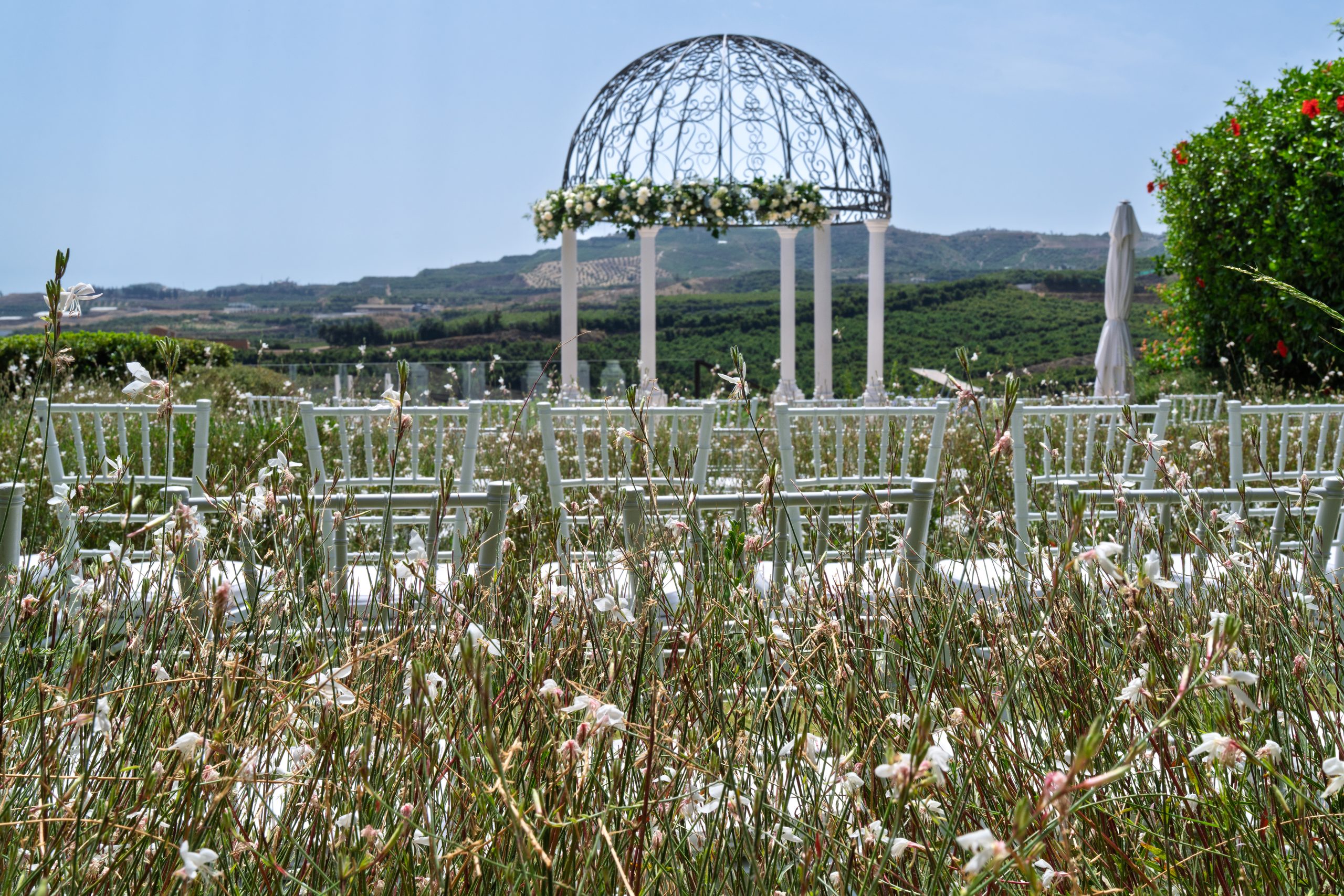 Sillas de la ceremonia y templete de hierro entre hierbas silvestres sobre el valle — Cortijo Bravo, Vélez-Málaga