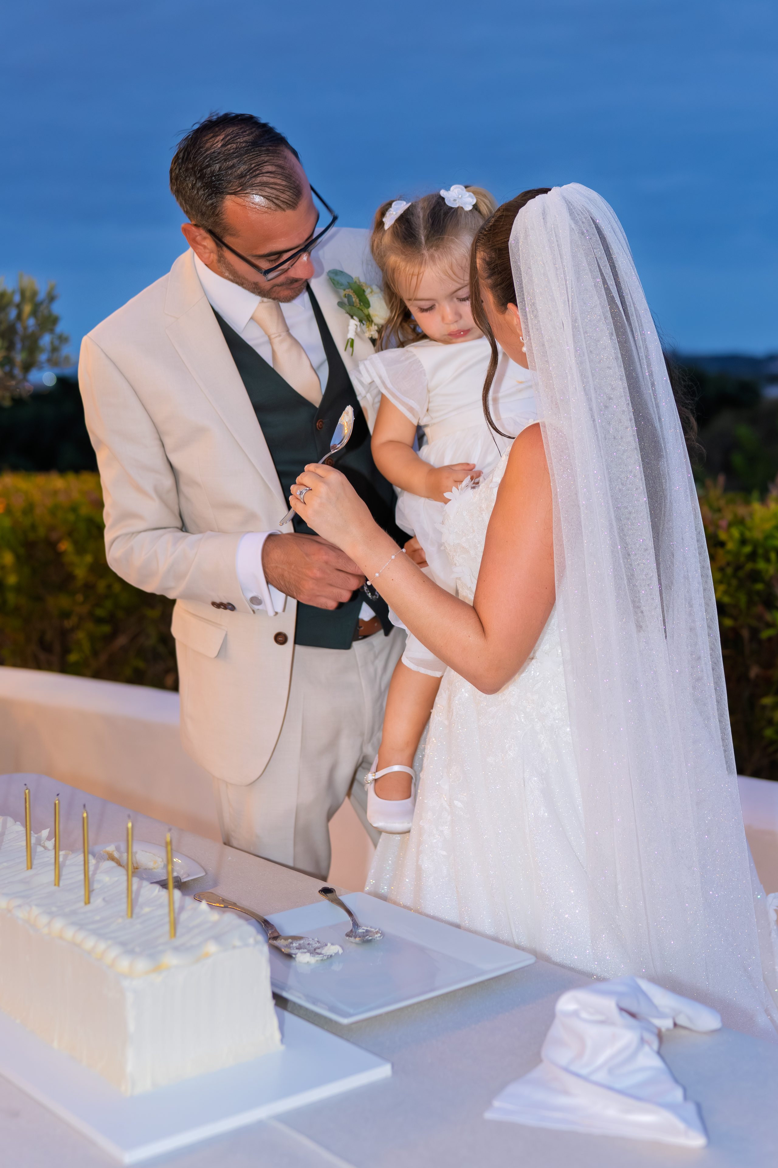 Les mariés tenant la fille de la mariée près de la table du gâteau — Cortijo Bravo, Vélez-Málaga