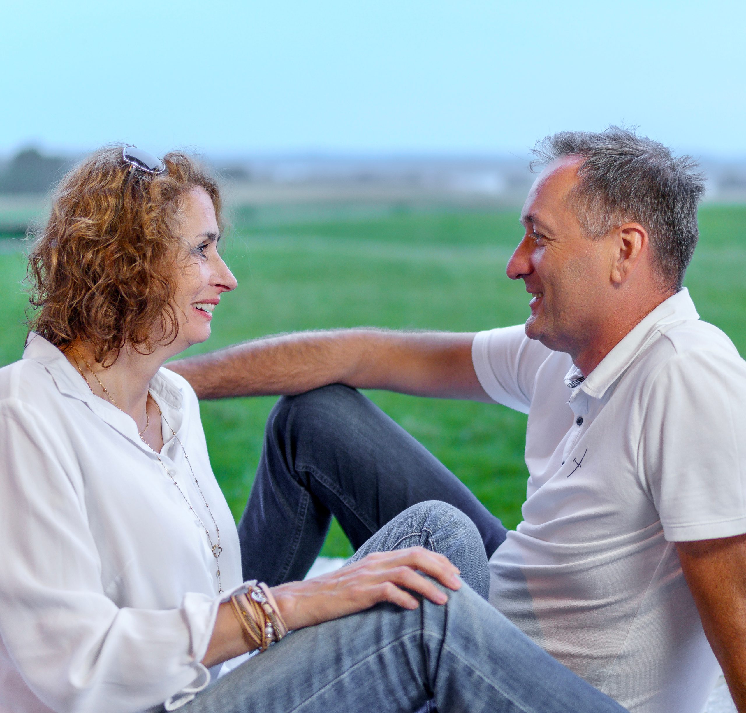Couple assis ensemble sur l'herbe, se souriant