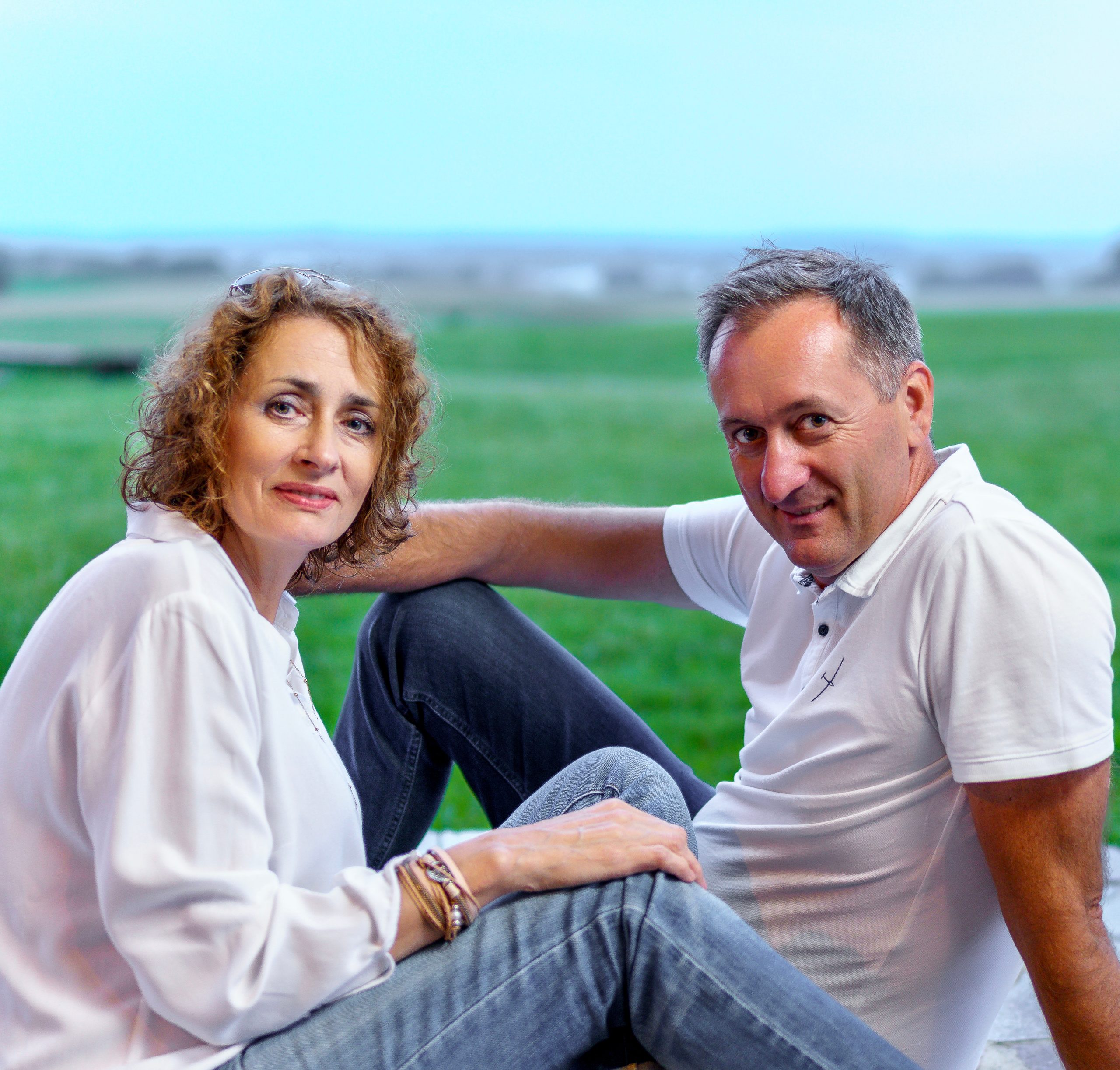 Couple assis sur l'herbe regardant l'objectif