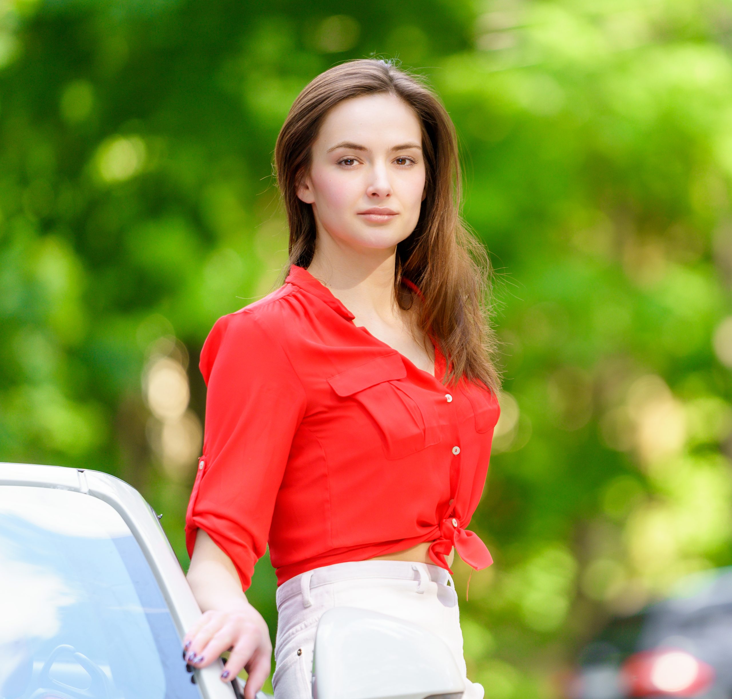 Portret młodej kobiety w czerwonej koszuli wśród zieleni