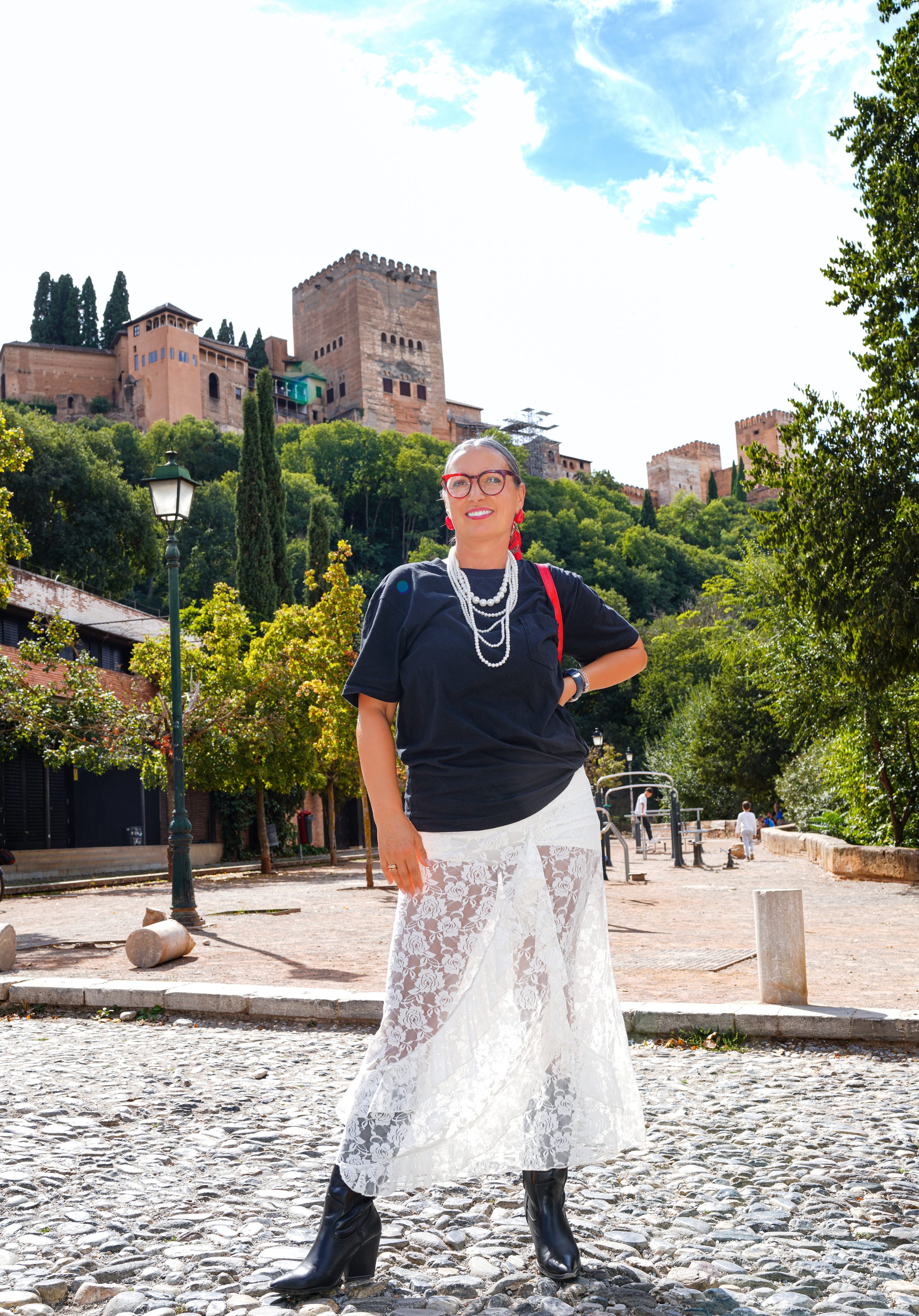 Kobieta na brukowanym placu, za nią Alhambra na wzgórzu — Paseo de los Tristes, Granada